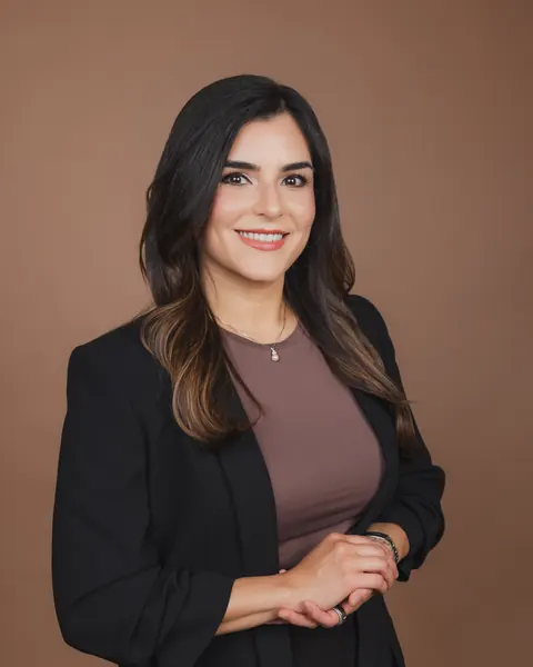 Headshot of a woman in a black blazer against a brown backdrop