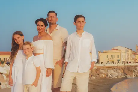 Family of five dressed in white on the beach at sunset