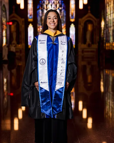 Graduate in gown and stole inside a chapel lit by candles and stained glass