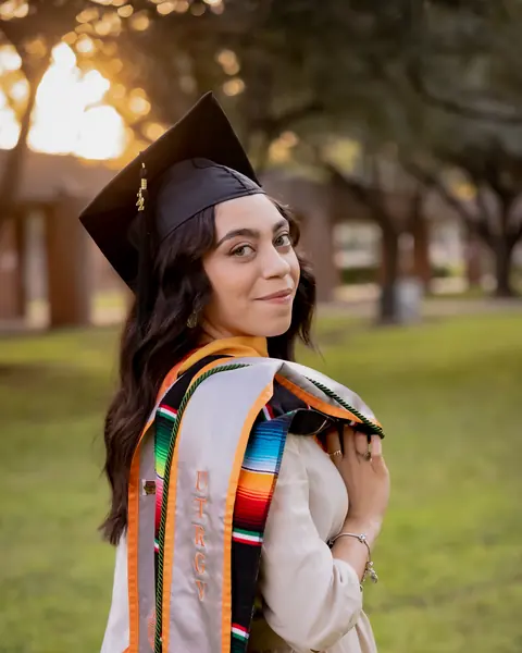 Graduate in cap and gown with a serape stole at golden hour