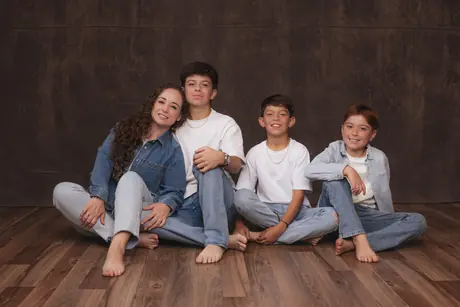 Four siblings in denim sitting on the studio floor