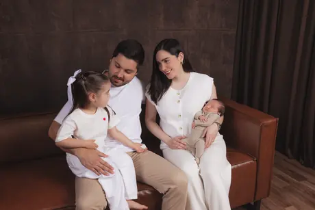 Parents with their newborn and their daughter on the studio sofa