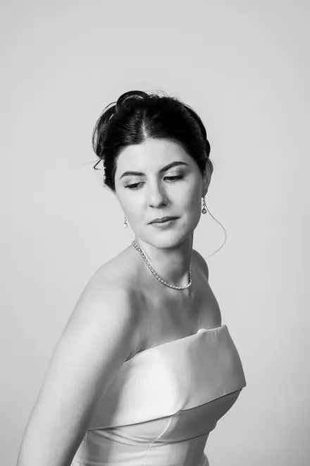 Woman in a white strapless gown looking down over her shoulder