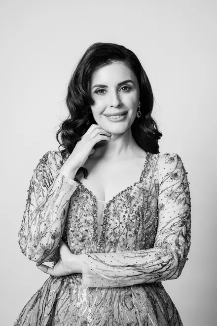 Woman in a beaded gown posing with her hand at her chin