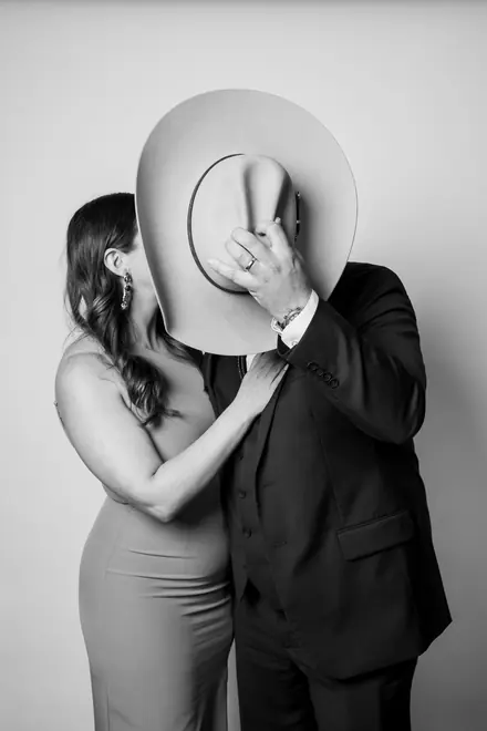 Woman hiding a kiss behind a man's cowboy hat