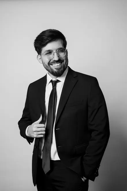 Smiling man in a suit and glasses adjusting his jacket