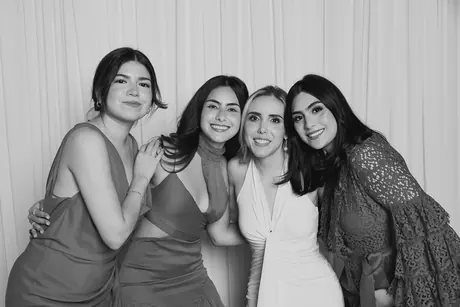Four friends in evening dresses leaning into each other
