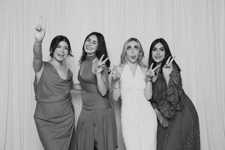 Four friends in evening dresses throwing peace signs