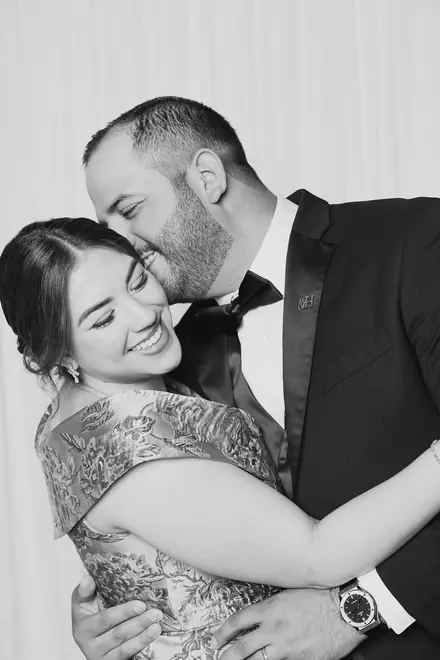 Man in a tuxedo kissing the cheek of a smiling woman