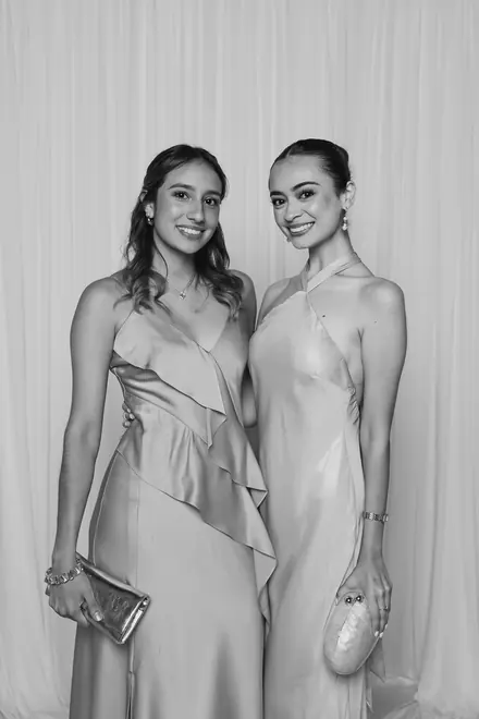 Two young women in satin dresses holding small clutches