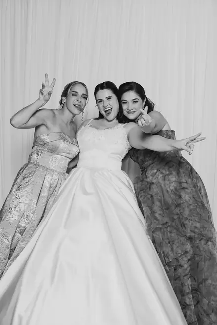 Woman in a white gown with open arms between two friends