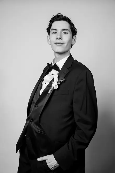 Young man in a tuxedo with a boutonniere, hands in his pockets