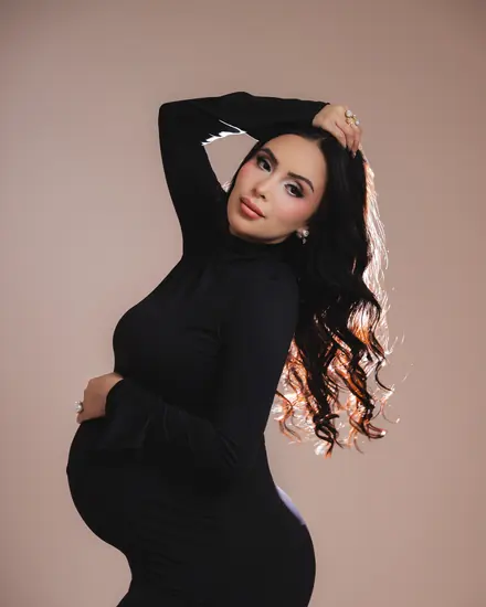 Expecting mother in a black dress posing in the studio