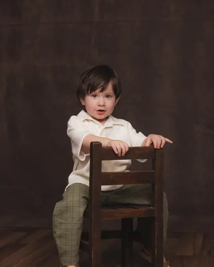 Toddler sitting on a wooden chair in the studio