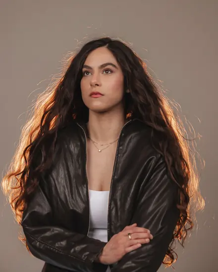 Portrait of a woman in a leather jacket, backlit against a warm backdrop